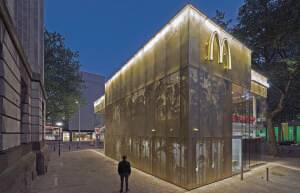 The smaller core is sheathed inside and out with a translucent screen made of gold anodized aluminum. That skin is perforated with heart-shaped openings to form a veil around portions of the glazed building through which illumination shines. This same skin is continued in the interior walls and ceilings. With the application of various degrees of perforation, the facade depicts a pixelated image of a crowd of people on Coolsingel. (JeroenMusch)