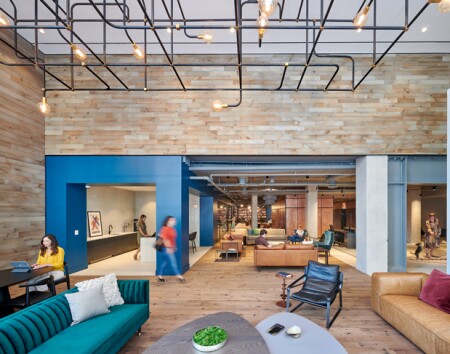 Residential lobby areas of the existing floor slab were cut away to create double-height spaces. Mechanical ductwork, conduits, and steel framing were left exposed to tell the story of this adaptive reuse project and to reduce the amount of materials used.  ©Judy Davis, Architectural Photographer