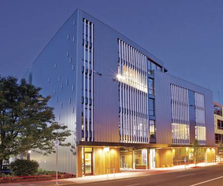 The Radiator Building glows at night along an enlivened North Vancouver Avenue only two miles (3.2 km) from the heart of downtown Portland, Oregon. Four-story vertical sunshades look like giant radiators, inspiring the building’s name. (Kaiser Group)