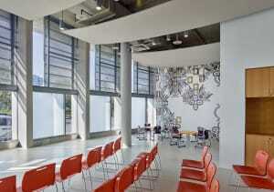 The glass-and-concrete community room faces out to the street and Channel Park beyond. The wall painting is by Julie Chang. (Bruce Damonte)