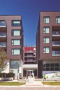 Residents and visitors traverse a bridge over a water feature before entering the building lobby. (Latrielle Delage Photography/Perkins + Will)
